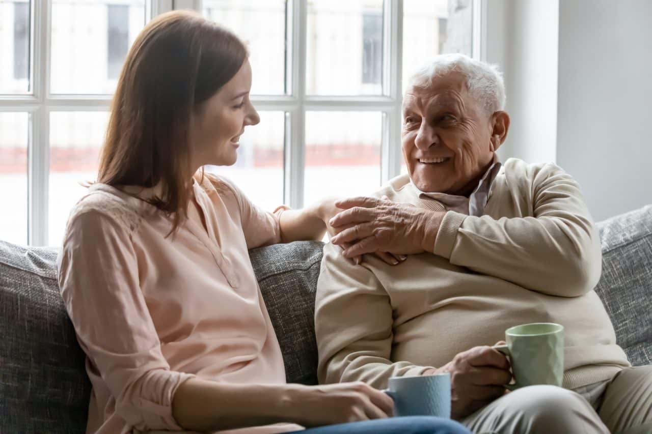 Adult daughter talking with her older father at home.