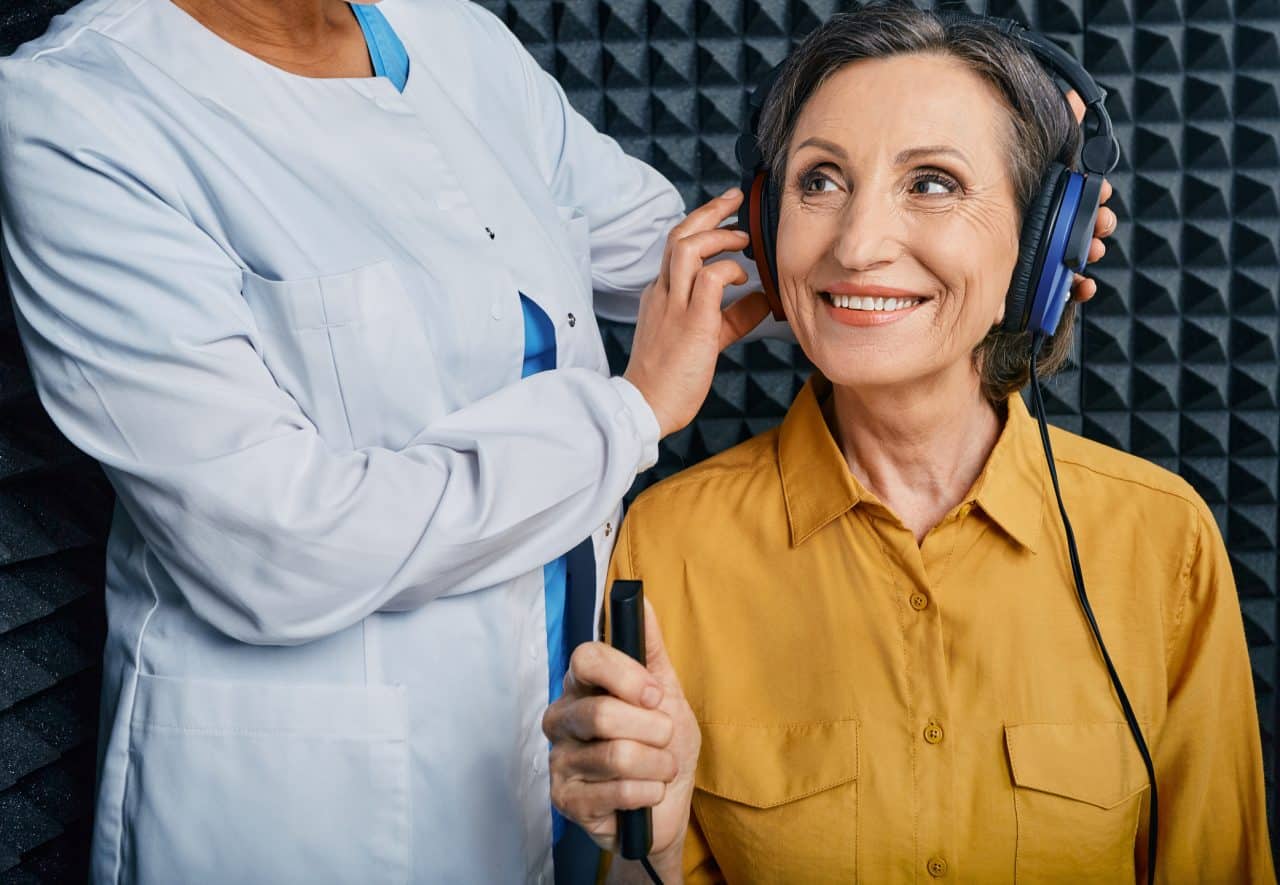 Woman getting a hearing test from an audiologist in a sound booth.