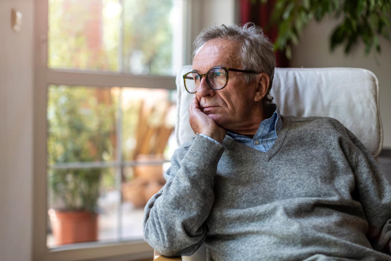 Older man looking pensively out the window.