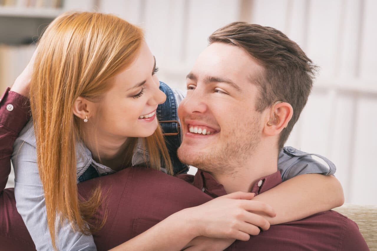 Smiling young woman loving her hearing impairment man