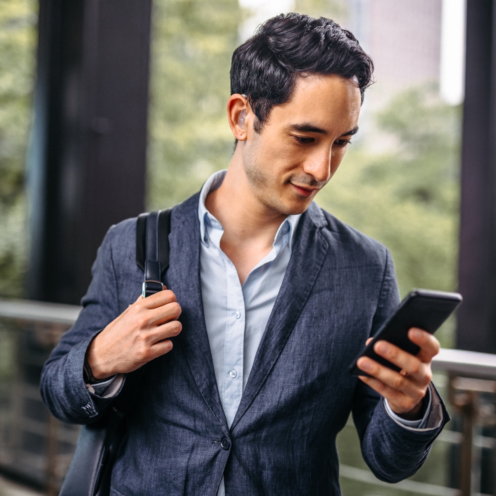 man with hearing looks at phone