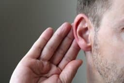 close-up image of a man touching his ear