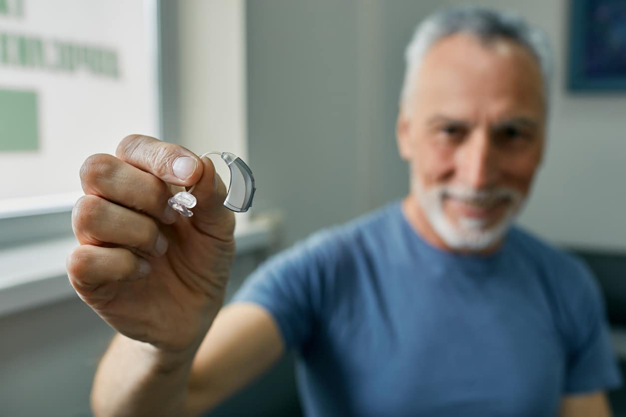 Senior man holding a BTE hearing aid.