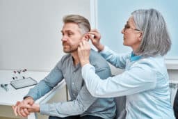 Hearing specialist fits a man for hearing aids