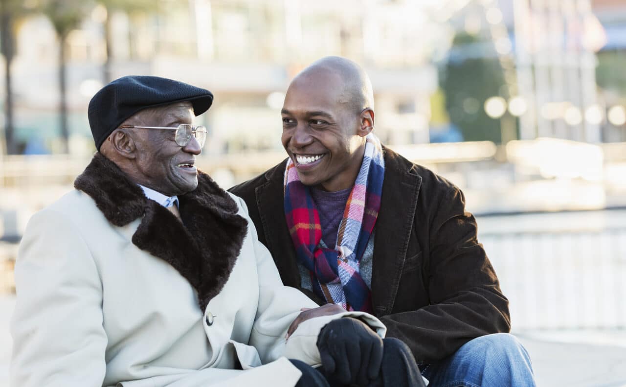 Grandson and Grandpa having a happy chat on a park bench.