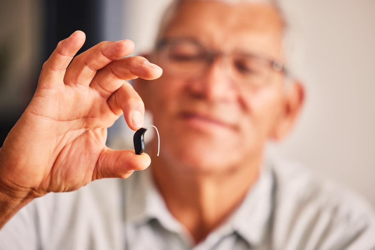 Senior man holding up his new hearing aid