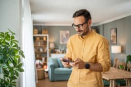 Portrait of cheerful man using smartphone at home
