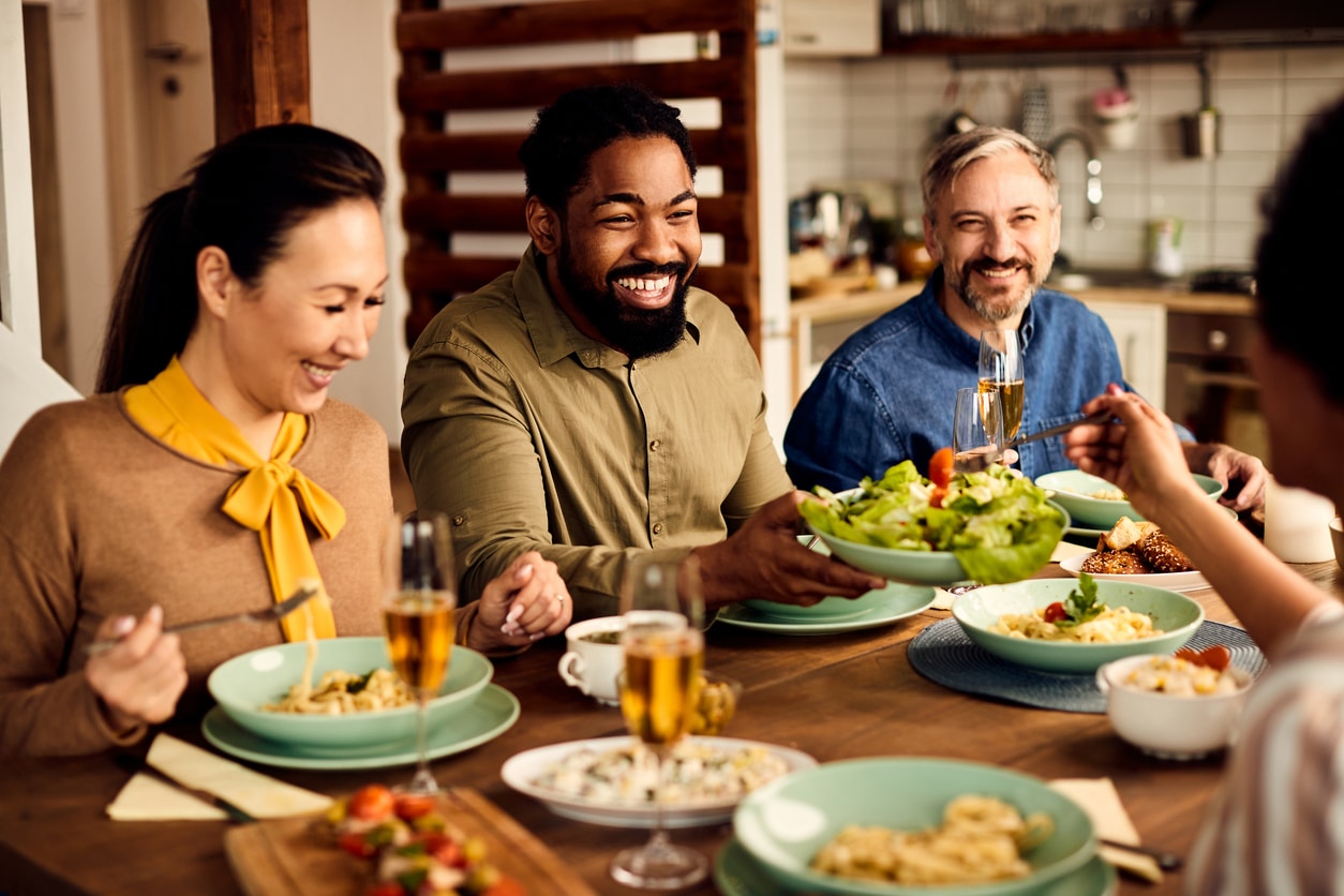 Group of happy friends eating lunch together at dining table